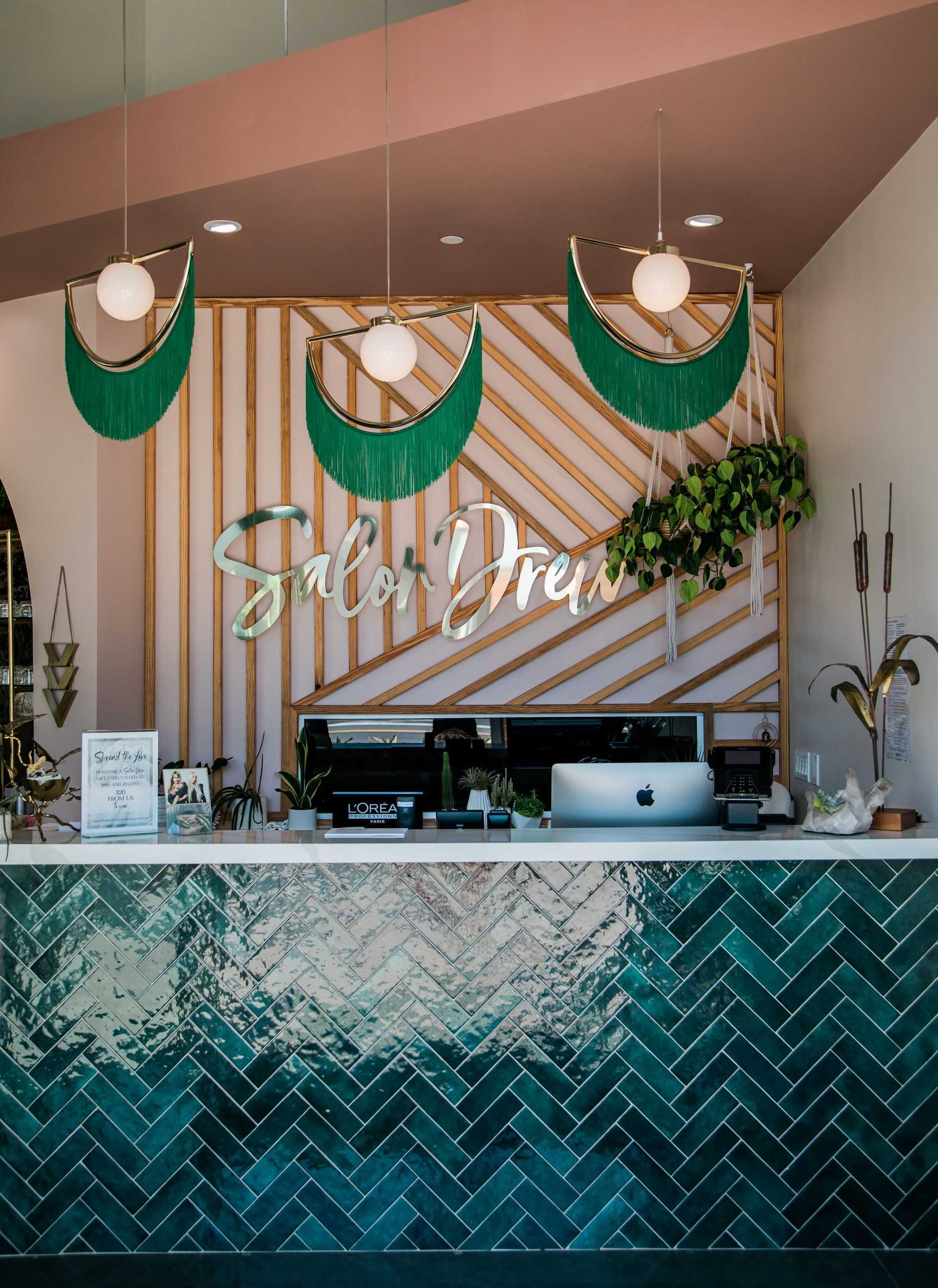 Reception of Salon adorned with green accents, plants, and stylish counter decor.