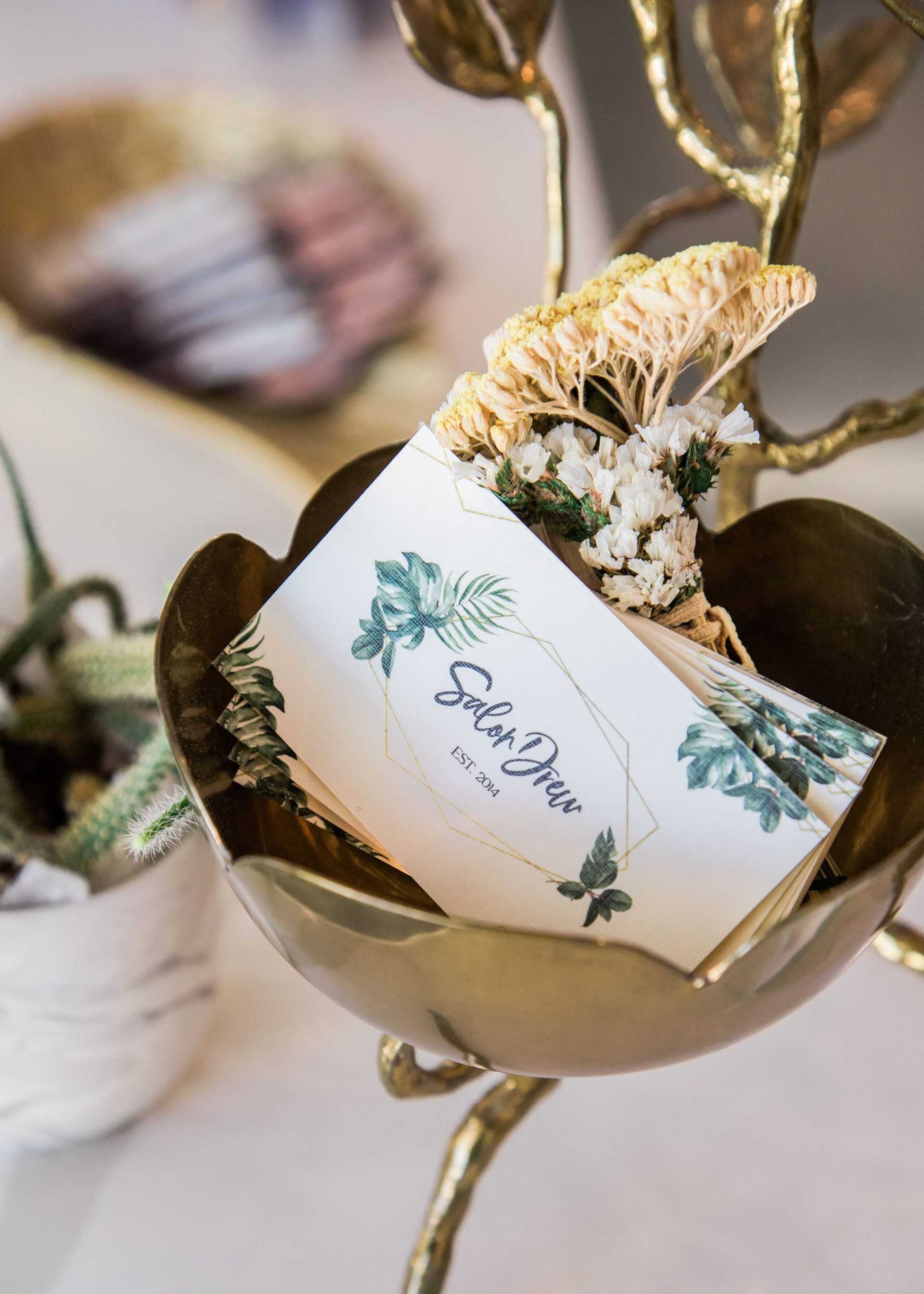 Floral-themed card holder with elegant invitations and dried flowers.
