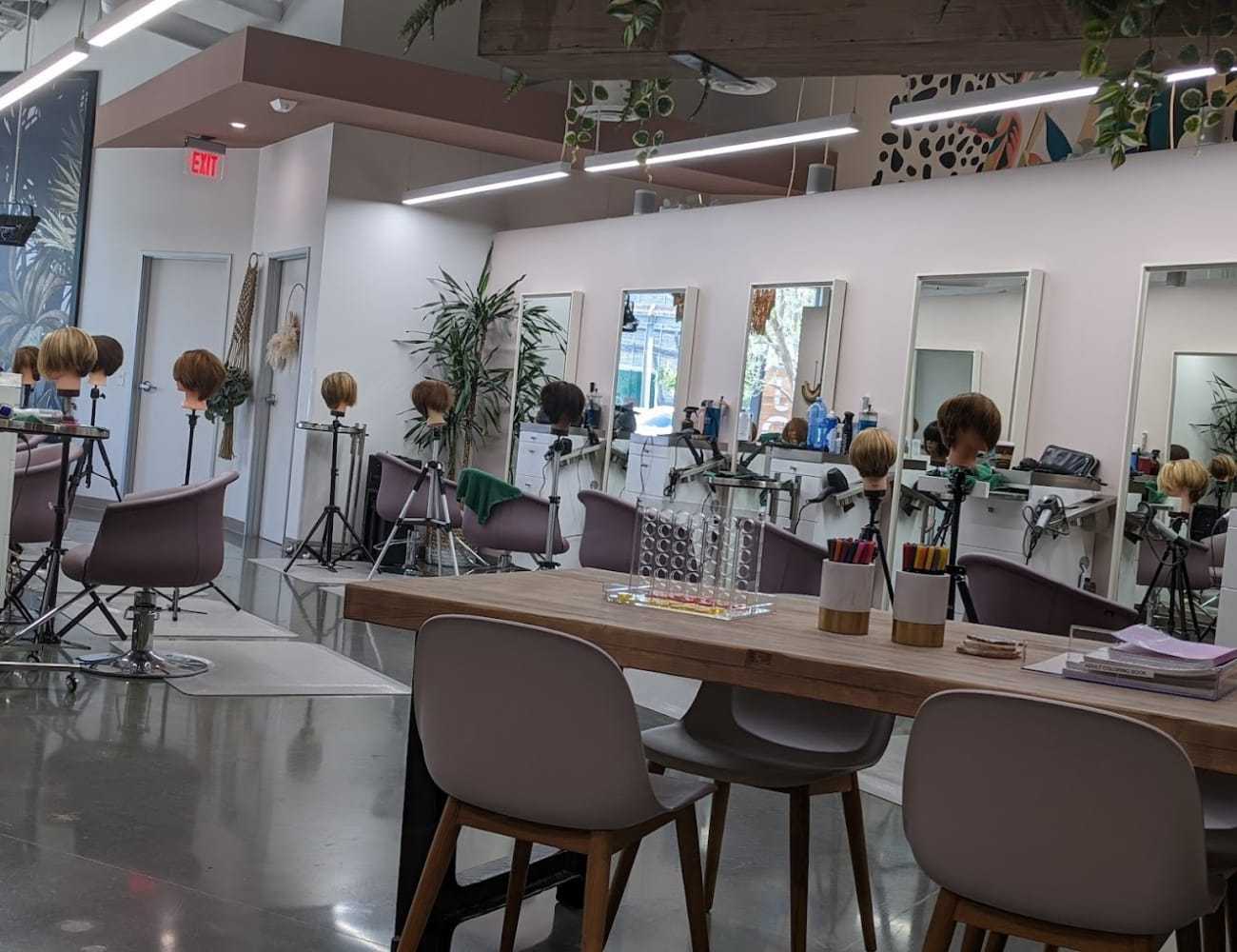 Modern hair salon with styling stations and mannequin heads for practice.